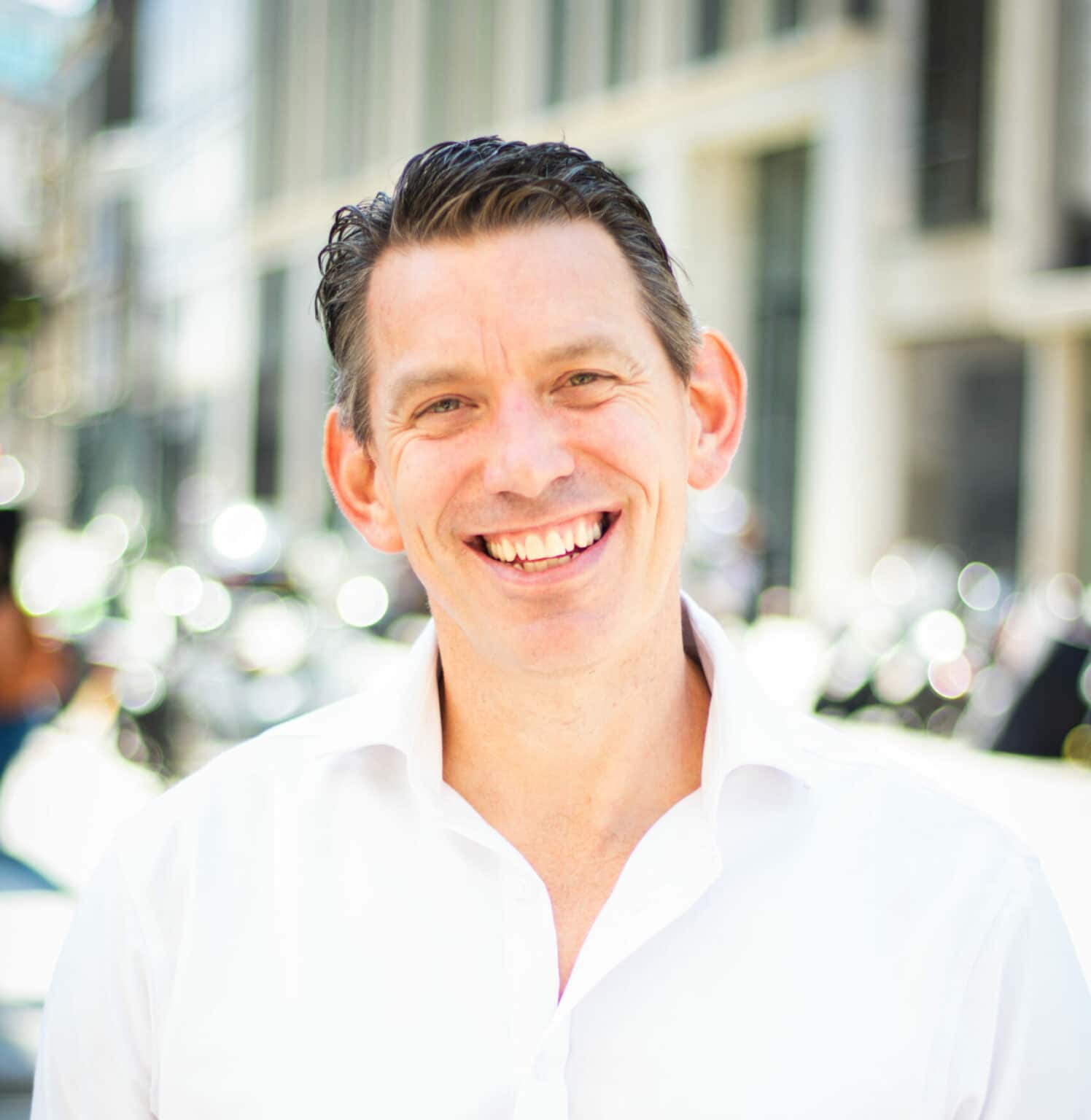Professional photo of a man smiling outside. Strong depth of focus
